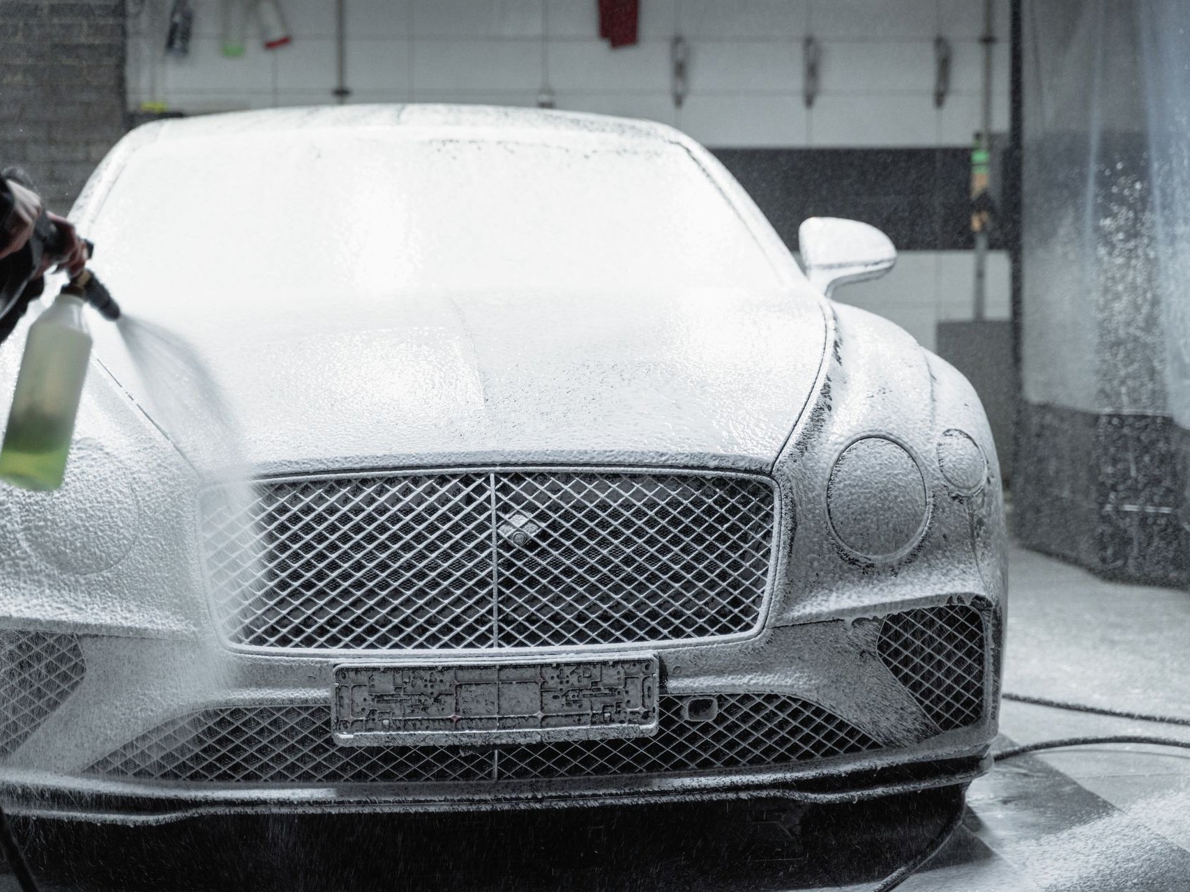 Luxury sedan covered in wash foam during a professional detail