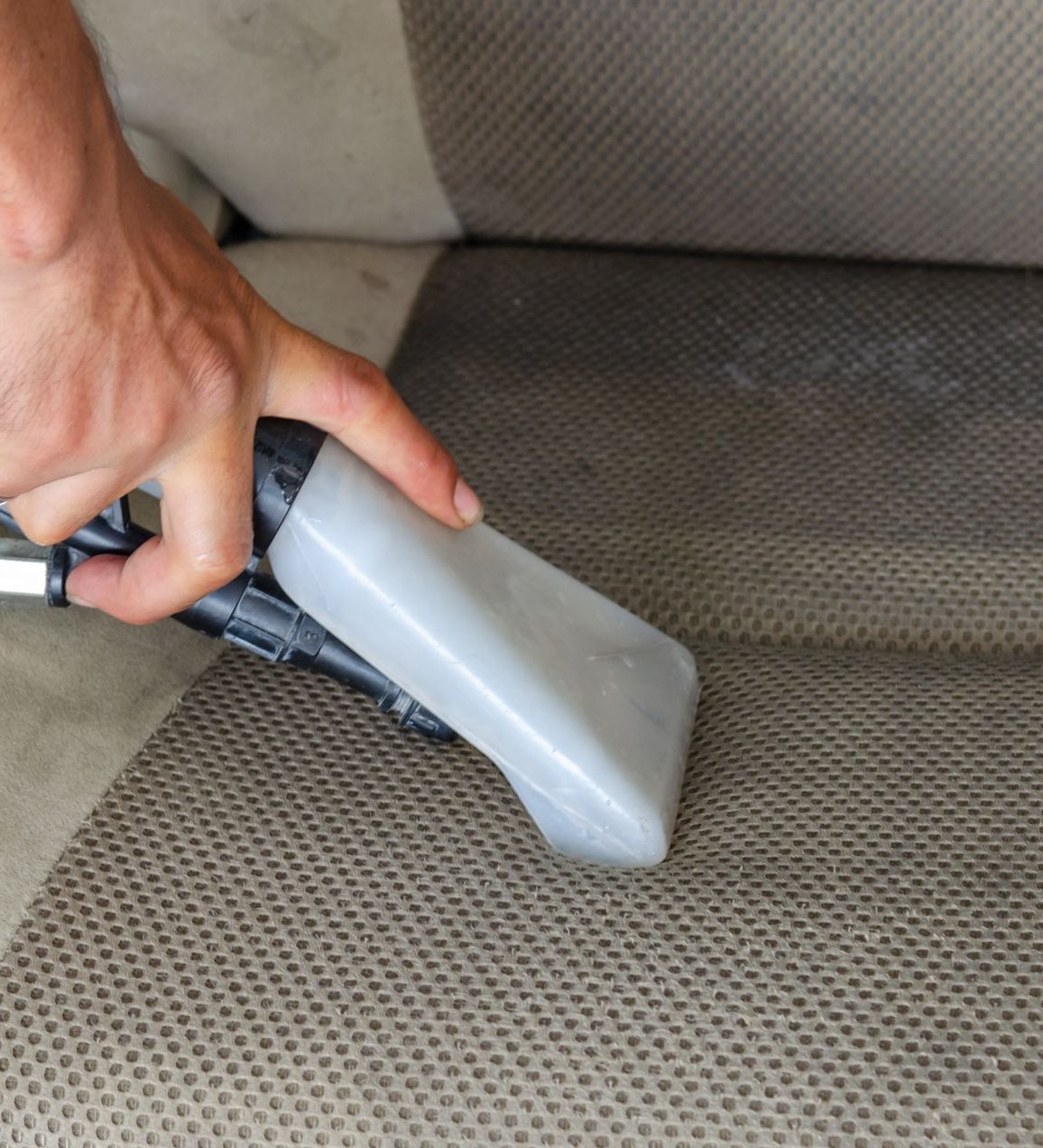 Car seat interior being deep-cleaned with a steam and extraction tool